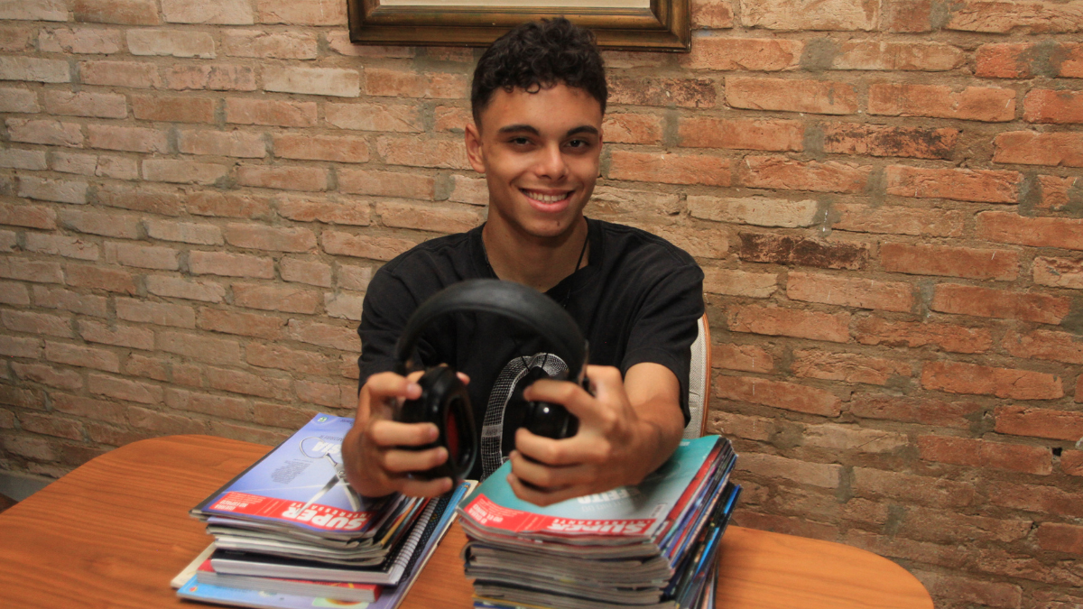 Jovem autista sorridente segurando cartazes de aprovação na universidade federal